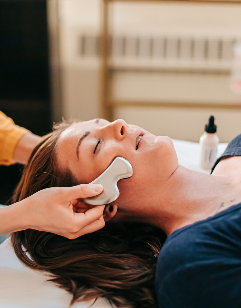 Woman relaxing during gua sha facial massage during an Acupuncture Glow Facial at Seneca Falls Acupuncture.