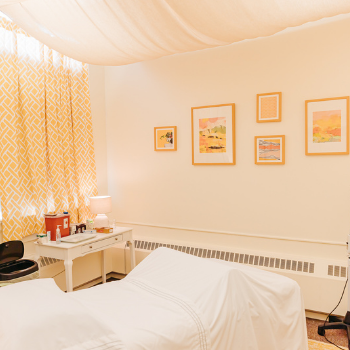 Photo of a treatment room at Seneca Falls Acupuncture with yellow curtains and bright, sunny art.