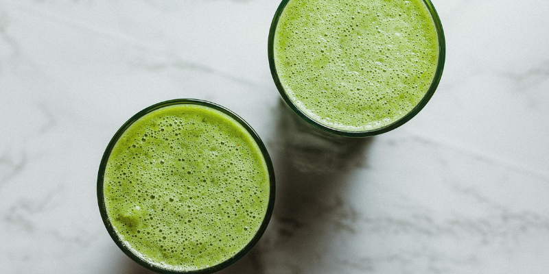 Image of green smoothies on a gray and white marble countertop.