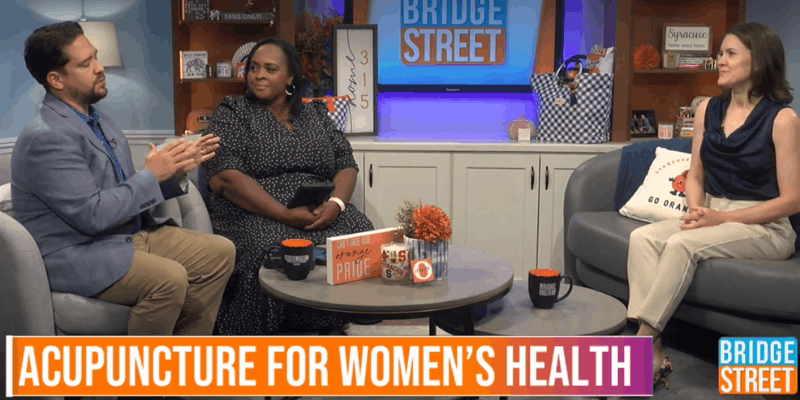 Photo of Michelle Grasek, clinic director at Seneca Falls Acupuncture, speaking with Bridge Street hosts Iris St. Meran and Erik Colombia on set about acupuncture for women's health.
