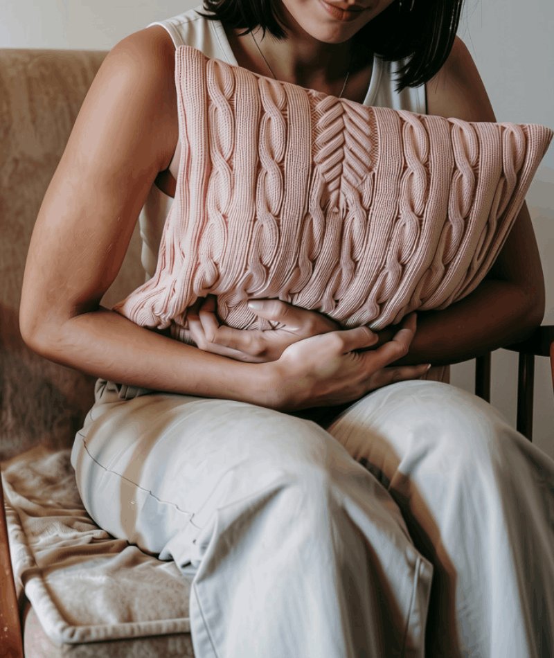 Image of a woman hugging a pillow in discomfort from digestive symptoms